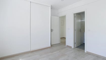 Suite bedroom with floor-to-ceiling wardrobe and ensuite bathroom doorway in Massamá