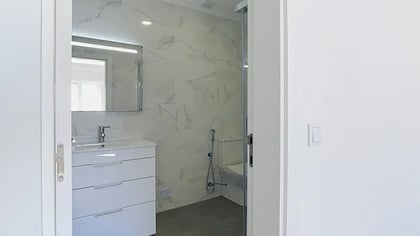 Modern bathroom with marble-effect tiles, vanity unit and dark floor tiles in Massamá