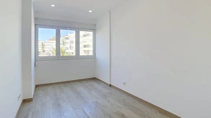 Bright empty bedroom with large window overlooking Massamá residential buildings