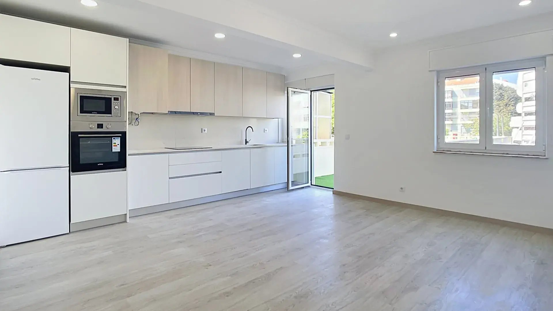 Fully renovated kitchen opening onto a light-filled living space with terrace access in Massamá