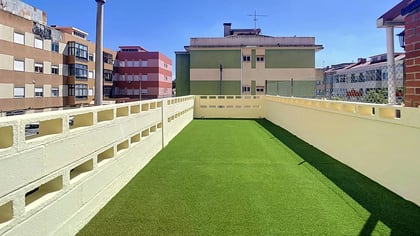 Long private terrace with artificial turf overlooking residential Massamá on a sunny day
