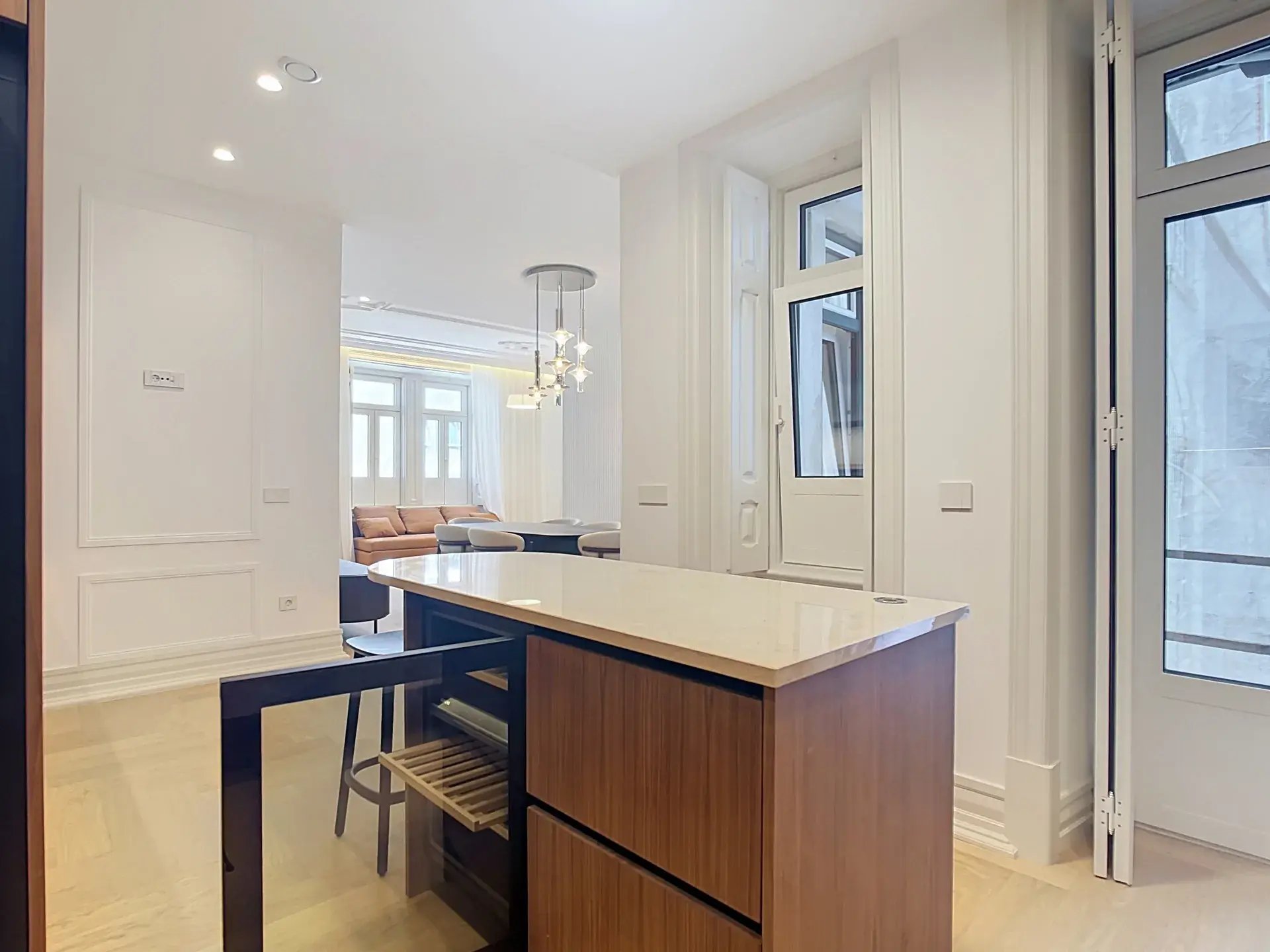 Kitchen island with stone countertop opening onto the living and dining area of a luxury Lisbon apartment