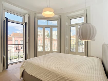 Master bedroom with curved façade and French doors opening to wrought-iron balconies overlooking Lisbon
