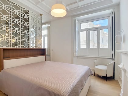Second bedroom with geometric lattice headboard wall and large shuttered window in a Lisbon T3 apartment
