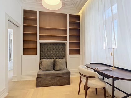 Study arranged as a flexible third bedroom with built-in shelving and velvet reading nook