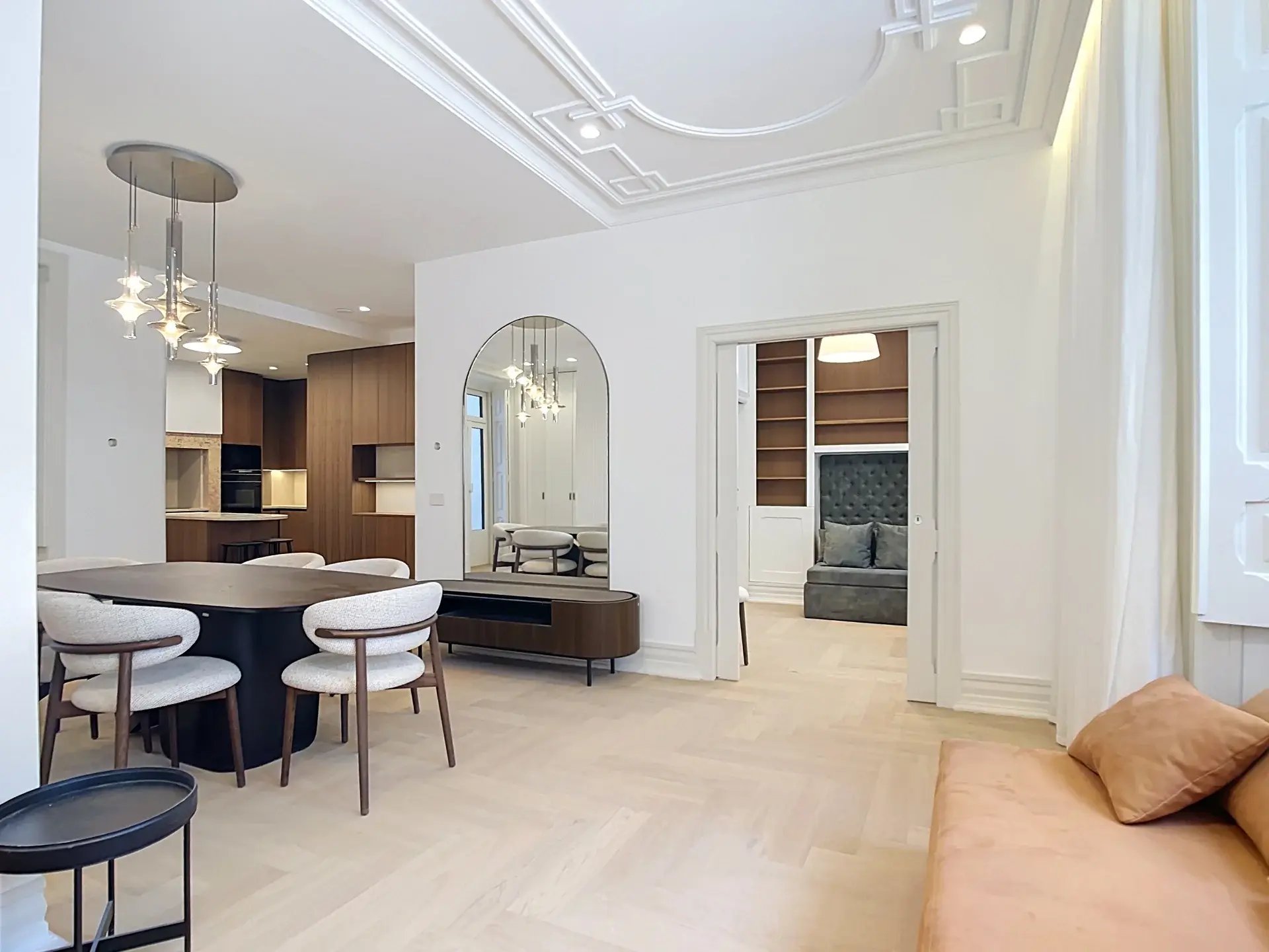 Open-plan dining area of a 3-bedroom apartment in Almirante Tridente, Lisbon, looking through to the kitchen and study with herringbone wood floors and classical ceiling moldings