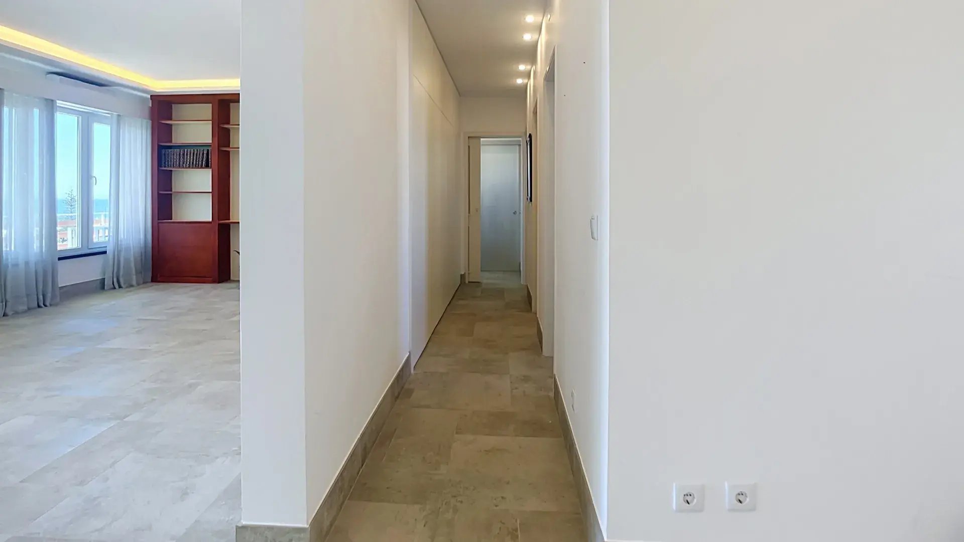 Hall and circulation beside the living room, with stone floors and a built-in bookcase