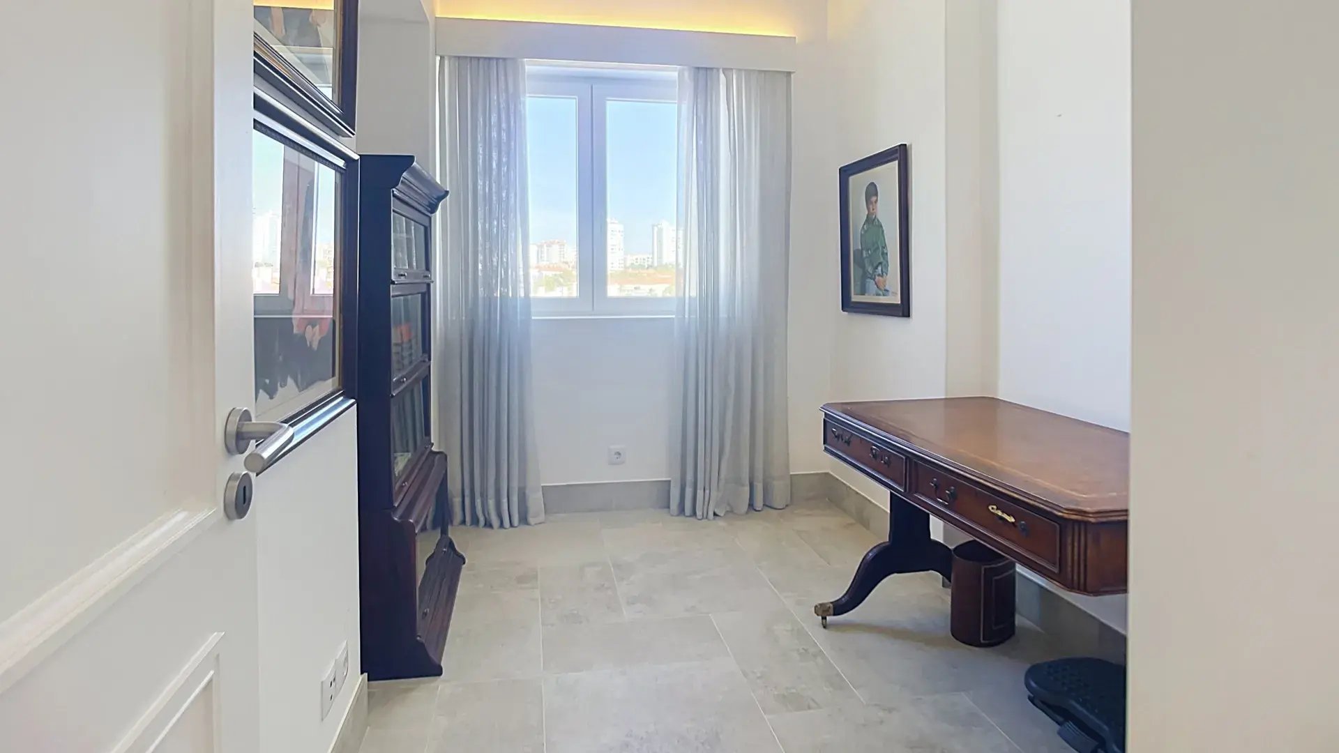 Study with a wooden desk and a window over Parede, usable as a flexible room