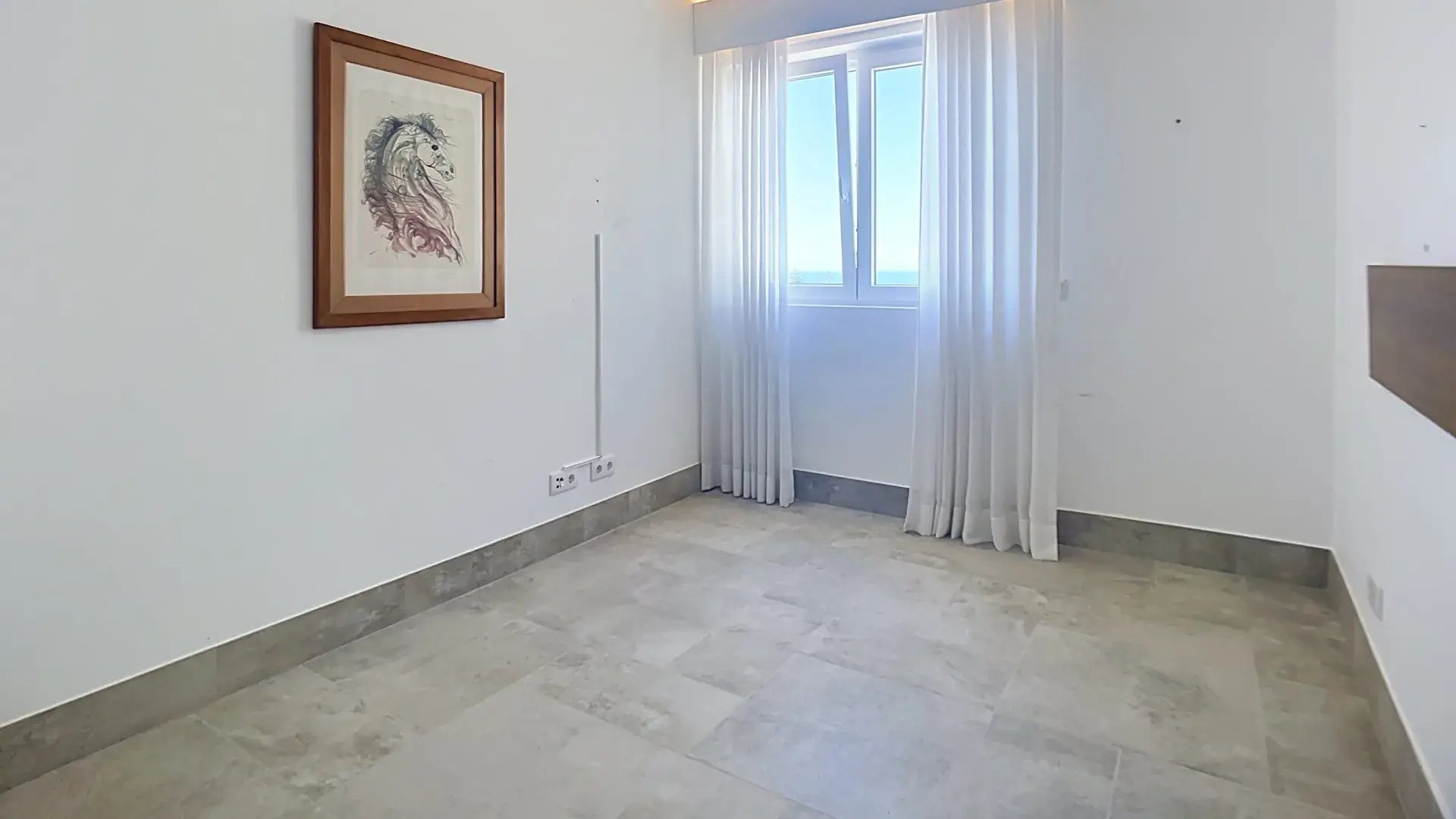 Bright bedroom with stone floors and a curtained window in the top-floor penthouse