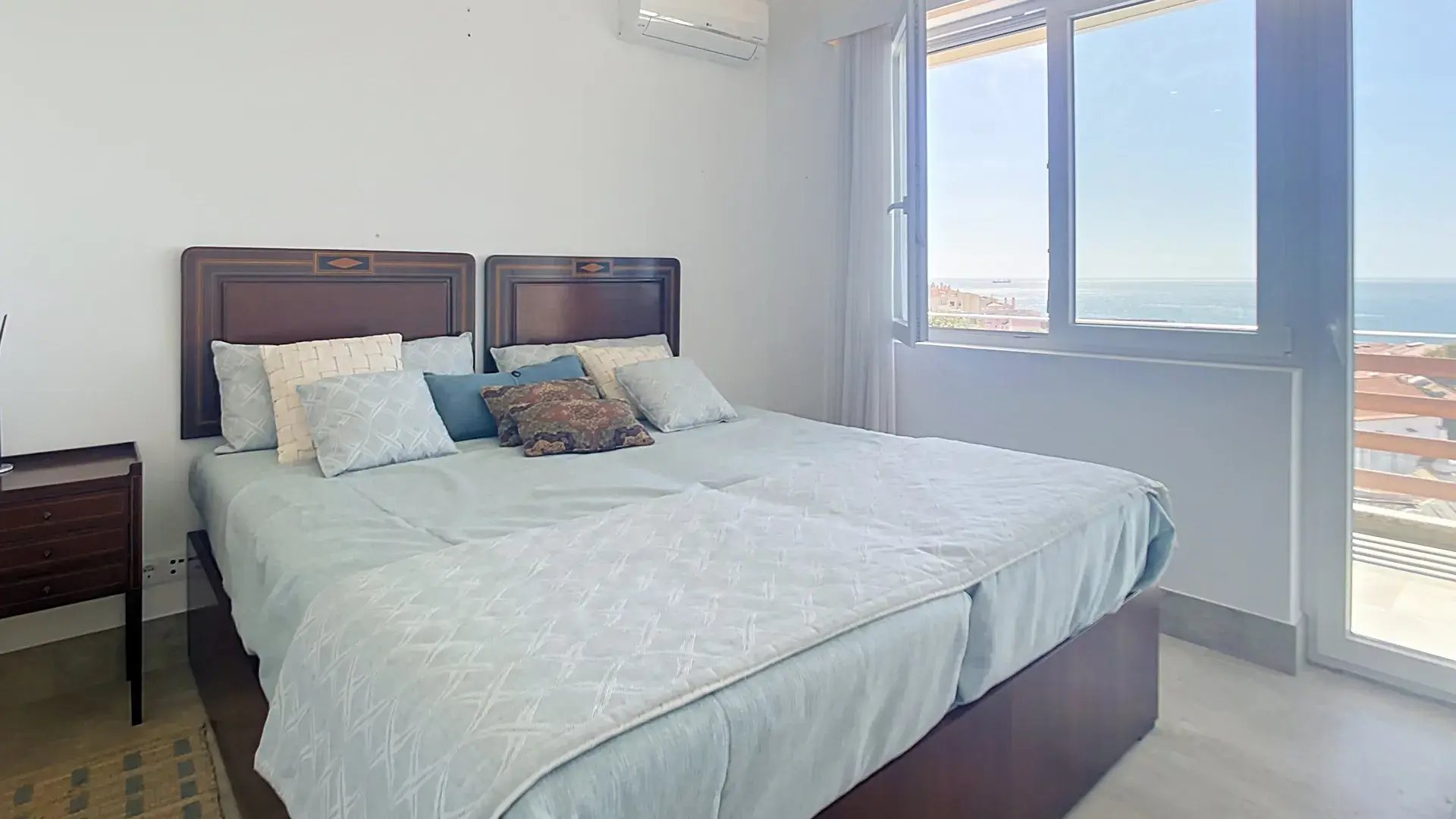 Bedroom with a double bed, wall-mounted air conditioning and a window onto the sea in Parede