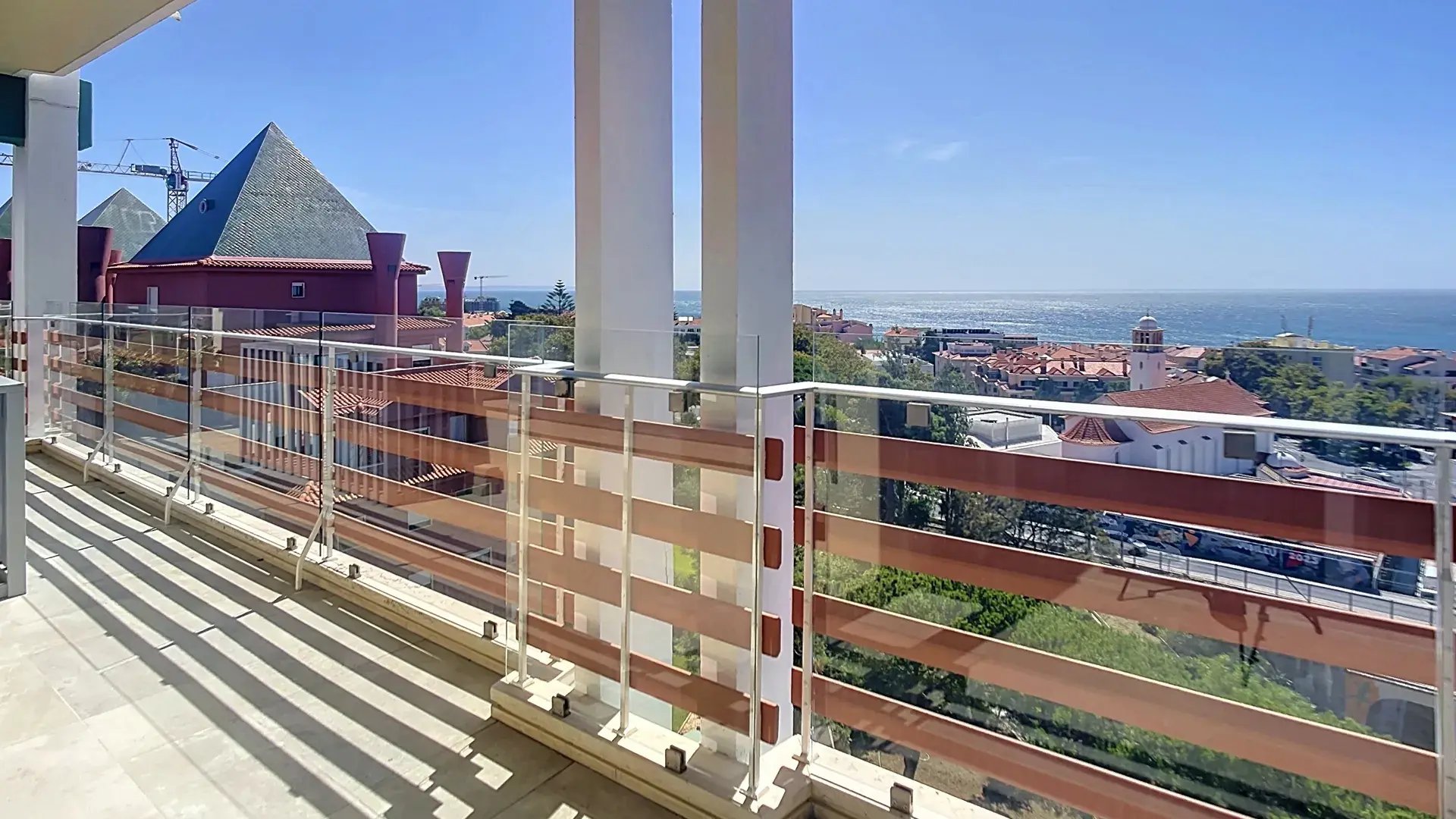 South-facing terrace with metal railing and a sea view over red rooftops in Parede