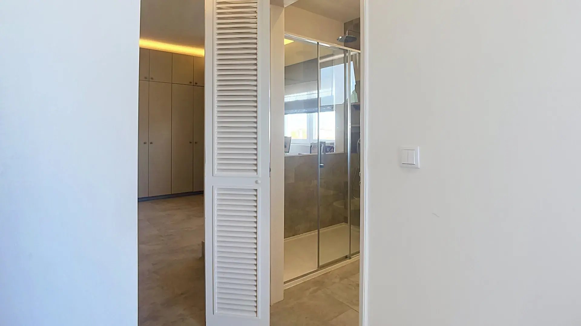 Built-in closet beside a glass walk-in shower in the Parede penthouse