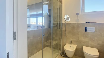 Bathroom with a glass shower, wall-hung WC and a window