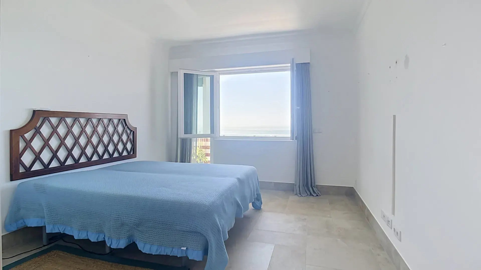 Bedroom with a wooden lattice headboard and a bright window in the Parede penthouse
