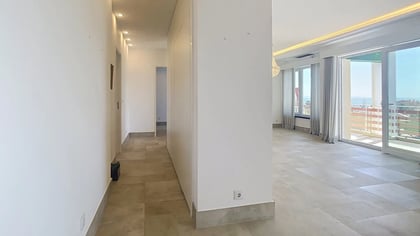 Wide living area with stone tile floors and a wall of windows in the Parede penthouse