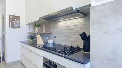 Kitchen with white cabinetry, black worktop and a gas hob in the Parede penthouse
