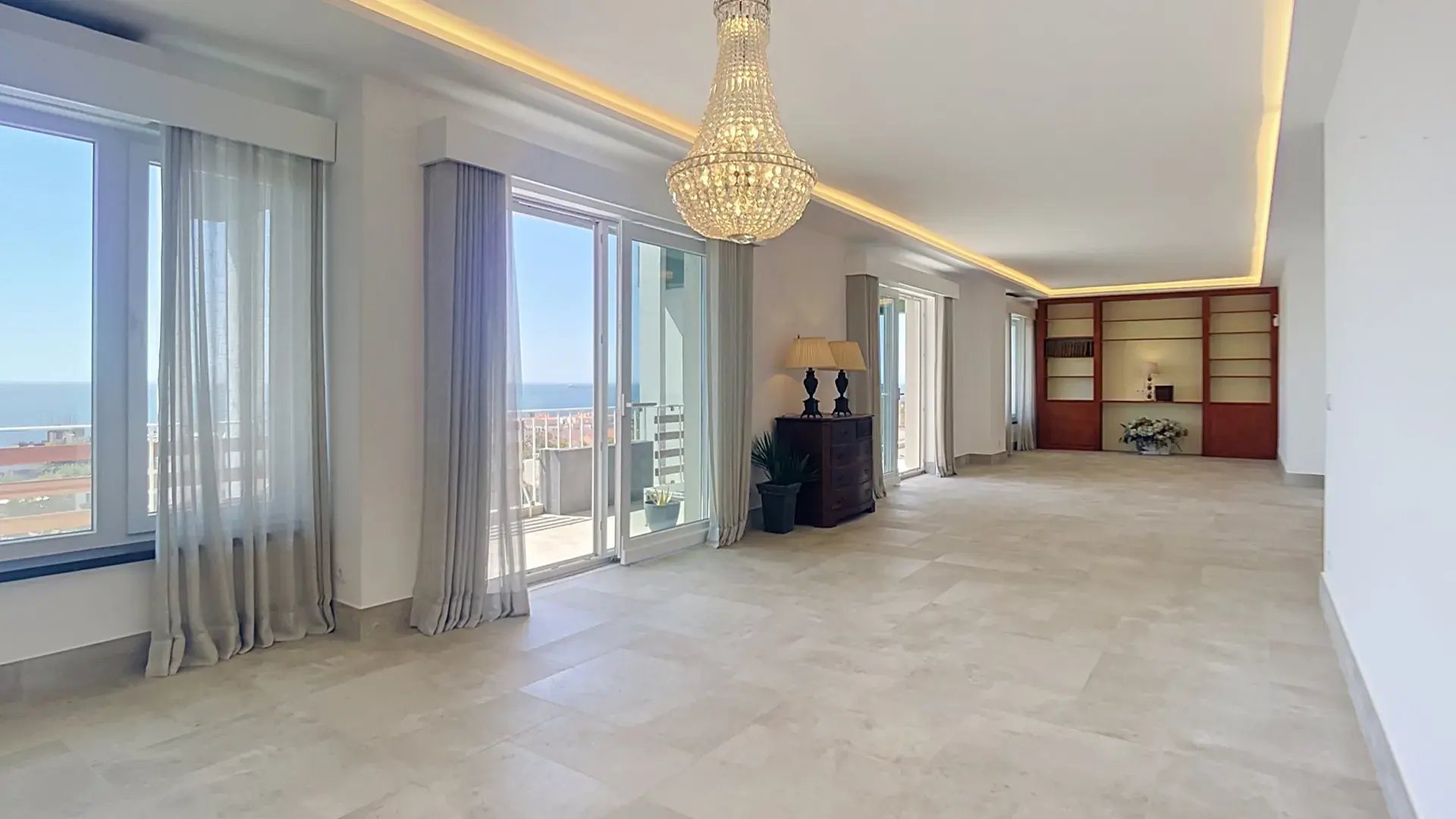 Living room of a top-floor penthouse in Parede, Cascais, with stone floors and windows opening onto the Atlantic