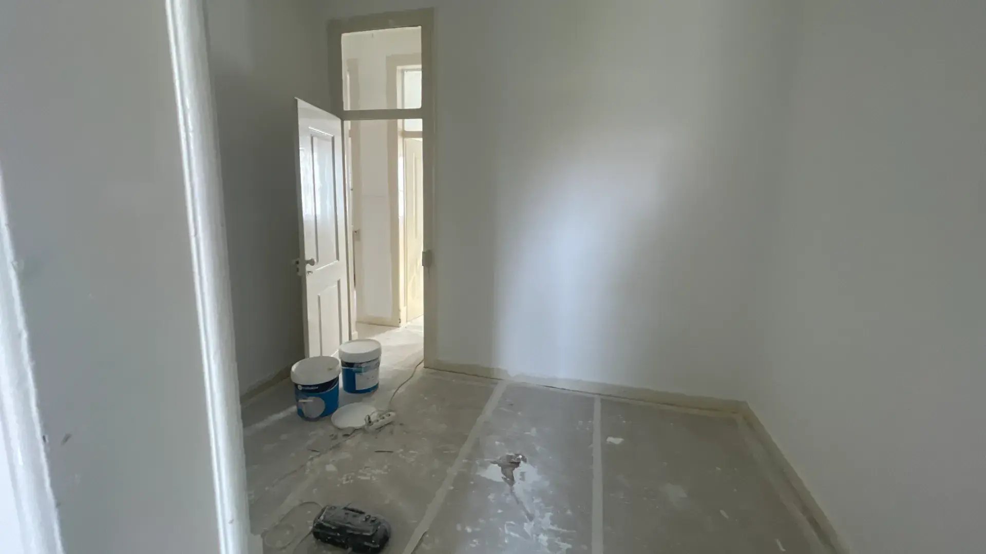 Empty room with decorative ceiling moldings, open shutters, and view of terracotta rooftops.