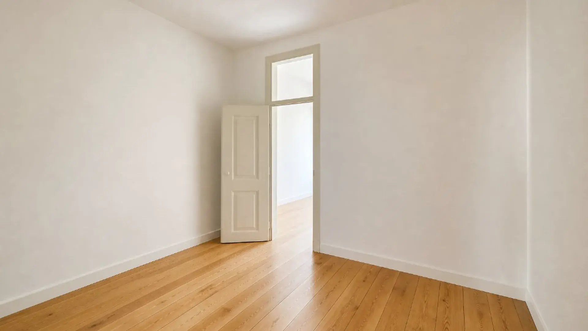 Room under renovation with floor protection, partial wood flooring, and window with city view.