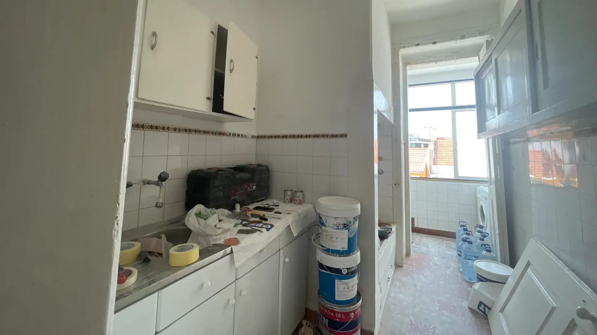 Virtual staging: bright kitchen with white cabinets, traditional mosaic floor, and view to a sunroom.