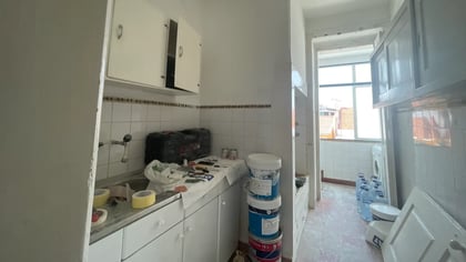 Virtual staging: bright kitchen with white cabinets, traditional mosaic floor, and view to a sunroom.