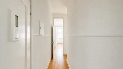 Empty room with open shutters and view of yellow façades and terracotta rooftops.