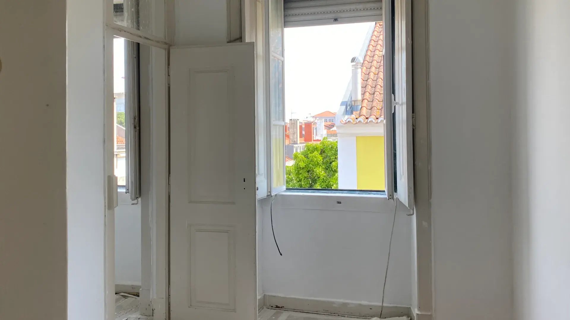 Room under renovation with floor protection, open door, radio, and electrical cables on the floor.