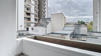 Vista exterior a partir da varanda do apartamento sobre edifícios urbanos envolventes num dia nublado.