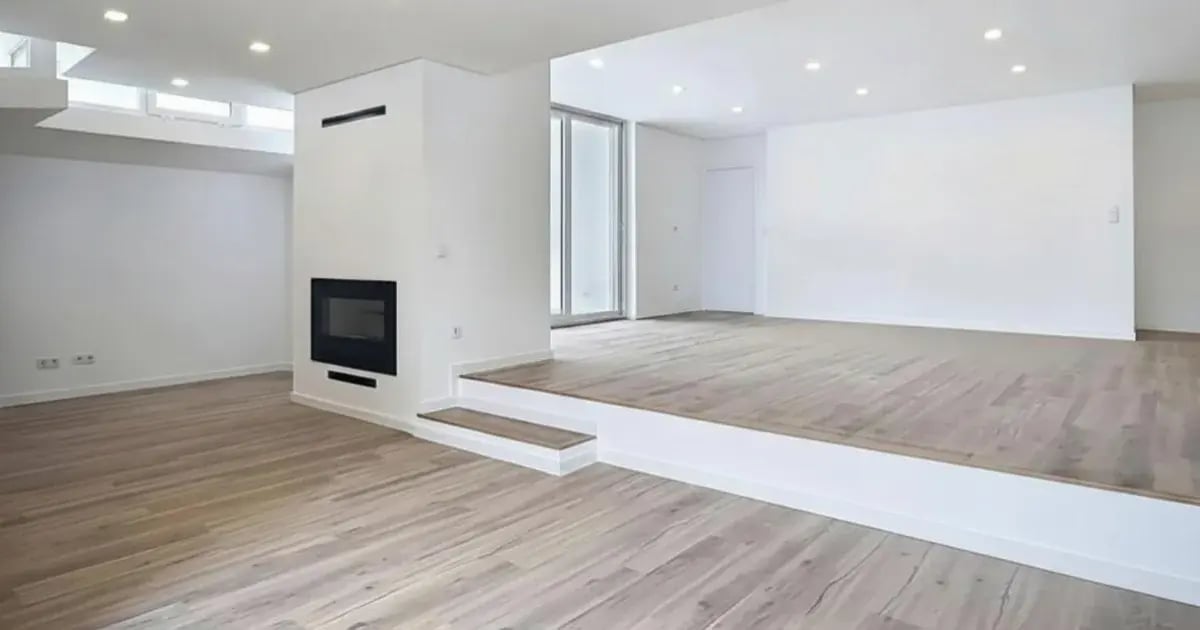 Sala de estar ampla e luminosa com pavimento em madeira clara, zona de estar em desnível e uma lareira moderna embutida